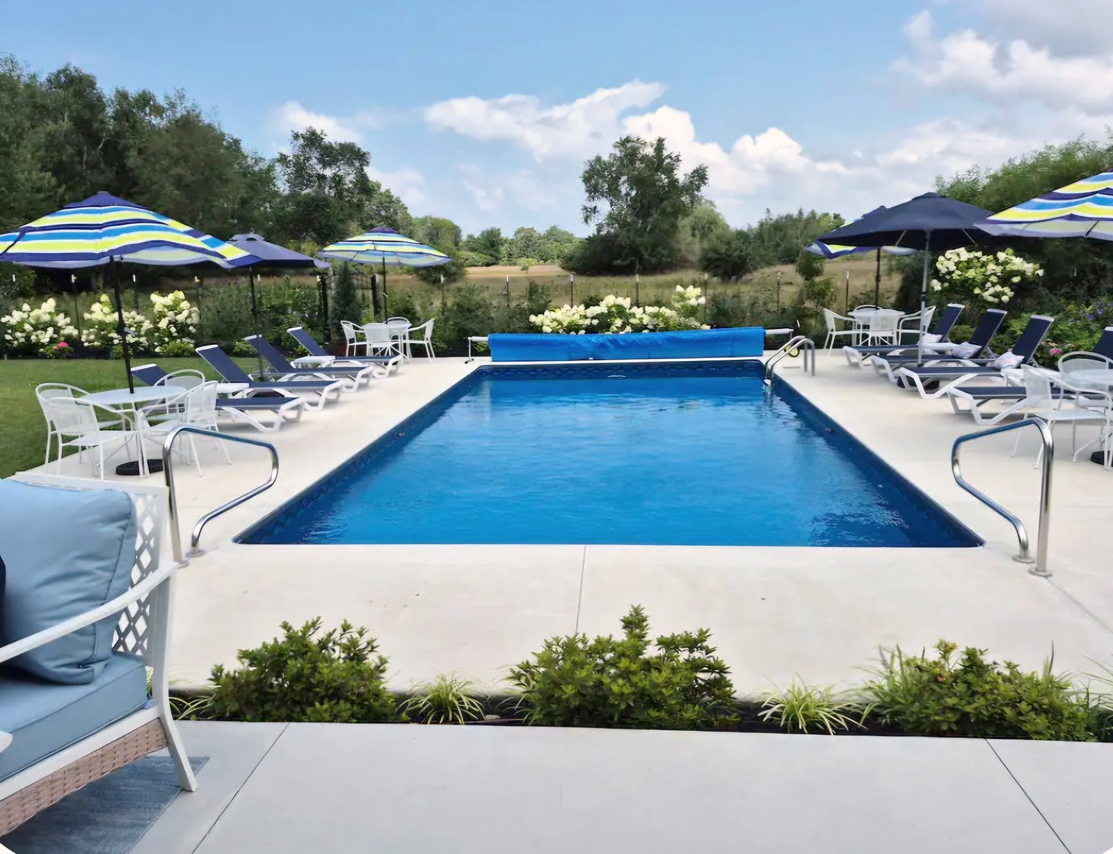 Heated saltwater swimming pool with sun loungers and open meadow backdrop